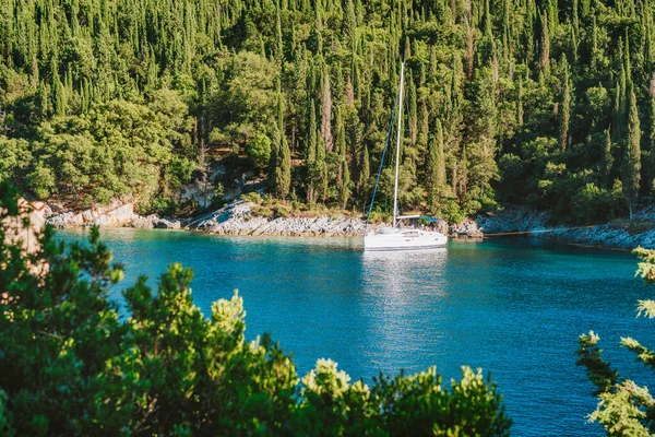 Vitorlás jacht kikötve az öbölben a Foki strand körül ciprusfák, Fiskardo, Cefalonia, Jón, Görögország — Stock Fotó