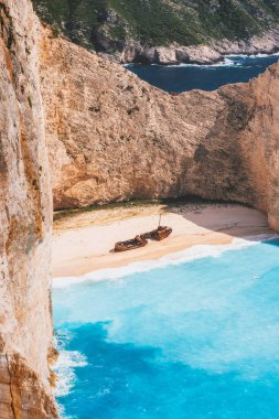 Zakynthos Adası, Yunanistan. Sıcak yaz gününde gemi enkazı olan ünlü Navagio plajı. Turkuaz su ve çakıl taşı plajı kireçtaşı duvarlarla çevrili.