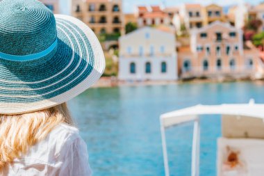 Güneşli bir günde, Assos köyündeki renkli sakin evlere yakından bakınca mavi şapka takan turist kadınlar görülüyor. Yazın Kefalonia 'yı ziyaret ediyorum. Yunanistan 'da seyahat tatili