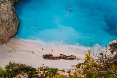 Naavagio sahilinde gemi enkazı. Gök mavisi turkuaz deniz suyu ve akşam ışığında cennet kumlu plajı. Yunanistan 'ın Zakynthos adasındaki tarihi yerleri ziyaret eden ünlü turist