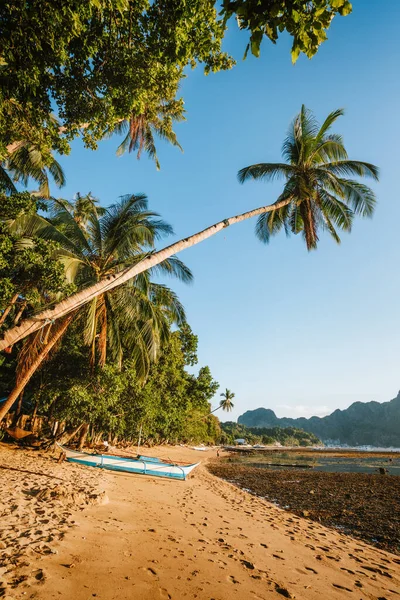 Luz dorada al atardecer en la playa tropical. Barco Bangka en la orilla bajo la palmera. Bahía El Nido. Palawan. Filipinas — Foto de Stock