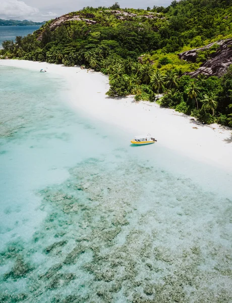 塞舌尔马埃岛蓝调清澈的泻湖中，一望无际的沙滩、棕榈树和孤零零的观光船 — 图库照片