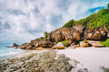 Seyşeller 'deki La Digue adasındaki Grand Anse plajı. En ünlü granit kayalar, beyaz kumlu plaj, okyanus gölü ve beyaz bulutlar.