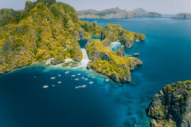 Palawan, Philippines aerial view of tropical Miniloc island. Tourism trip boats at big lagoon entrance. Natural scenery clipart