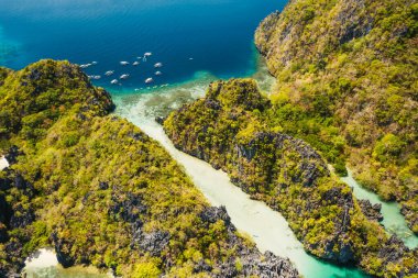 Palawan, Filipinler 'de tropik Miniloc adasının hava manzarası. Büyük lagünün girişine demirlemiş turizm tekneleri.