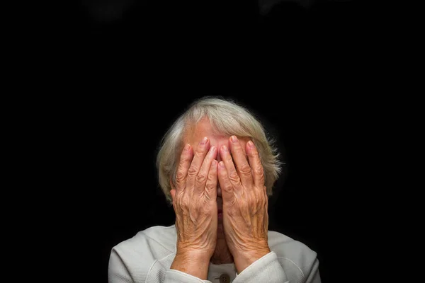 Retrato de uma mulher idosa com o rosto fechado por mãos — Fotografia de Stock
