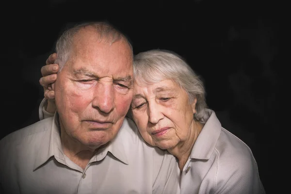 Грустная пожилая пара на черном фоне — стоковое фото