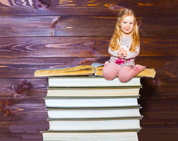 Niña sentada en una pila de libros — Foto de Stock
