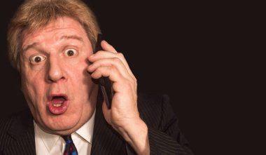 Şok haber. Cep telefonu ile takım elbiseli şaşırmış olgun adam