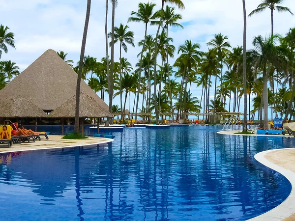 Punta Cana, República Dominicana - 04 de fevereiro de 2013: Turistas comuns descansando em Barcelo Bavaro Beach hotel com piscina sob as palmas das mãos — Fotografia de Stock