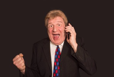 İyi haber. Cep telefonu ile takım elbiseli şaşırmış olgun adam