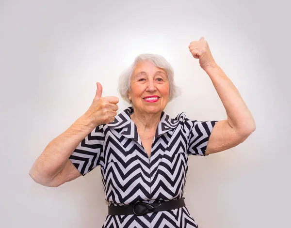Портрет веселой пожилой женщины, показывающей победу над розовым — стоковое фото