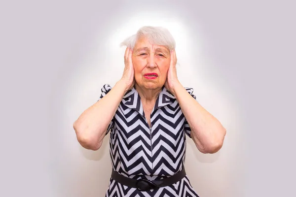 Старшая женщина с головой в руках выглядит усталой — стоковое фото