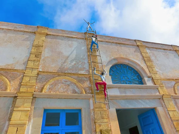 Oia, Santorini, Grécia - 10 de junho de 2015: Escultura de homens de escalada como decoração de edifícios antigos na cidade de Oia — Fotografia de Stock