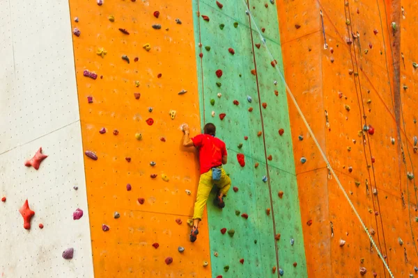 Le jeune homme actif sur la paroi rocheuse dans le centre sportif — Photo