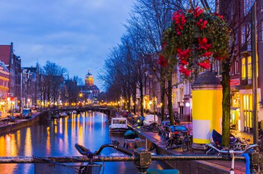 Amsterdam kanal ve Köprüsü gece aydınlatma ile tipik Hollanda evleri, tekneler ve Bisiklet.