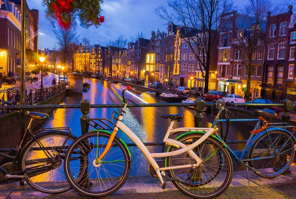 Ночное освещение Амстердамского канала и моста с типичными голландскими домами, лодками и велосипедами . — стоковое фото