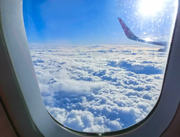 Vista da asa de um avião voando acima das nuvens. Nuvens e céu através de uma janela de avião — Fotografia de Stock