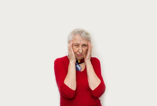 Una donna anziana poggia la testa su uno sfondo bianco — Foto Stock