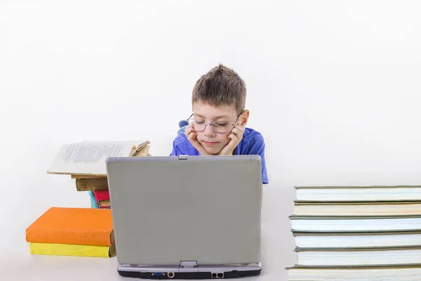 Retrato de colegial lindo sentado con libros y mecanografía en el teclado del ordenador portátil — Foto de Stock