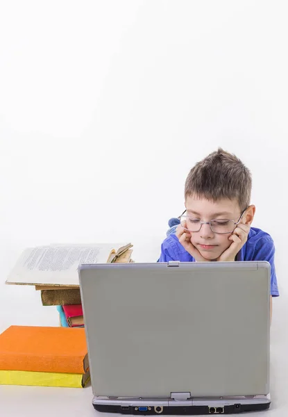 Retrato de colegial lindo sentado con libros y mecanografía en el teclado del ordenador portátil — Foto de Stock