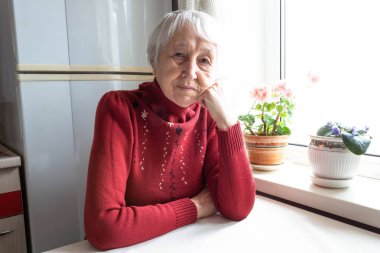 Elderly lonely woman depressed sitting at the table clipart