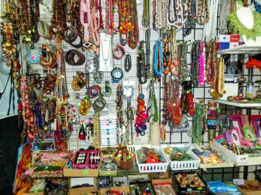 Etnik hediyelik eşyalar, beyzbol şapkaları, sokak pazarında asılı çeşitli desenli çantalar.