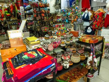 Etnik hediyelik eşyalar, beyzbol şapkaları, sokak pazarında asılı çeşitli desenli çantalar.