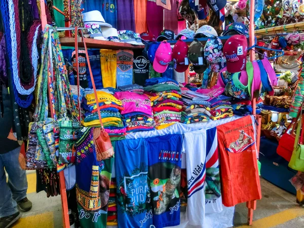 Puerto Limon, Kosta Rika - 8 Aralık 2019: Etnik hediyelik eşyalar, beyzbol şapkaları, sokak pazarında asılı çeşitli desenli çantalar — Stok fotoğraf