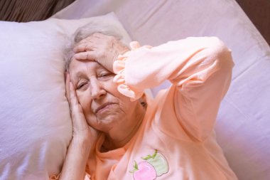 Coronavirus, Covid-19, sağlık, güvenlik ve salgın konsept, bakım, ağrı, stres, yaş ve insan konsepti - evde baş ağrısı çeken yaşlı kadının yüzü