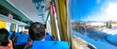 Otobüste oturan ve ormanın penceresinden bakan bir grup turist.