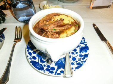 Soyut yolcu gemisinin restoranında keçi peynirli kraker ile bir kase Fransız soğan çorbası.