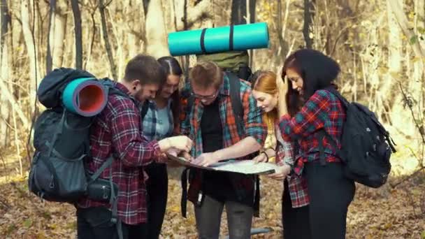 Mladí turisté hledají na mapě správný směr v podzimním lese — Stock video