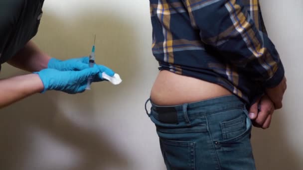 Медсестра делает инъекцию ягодиц пациенту мужского пола — стоковое видео