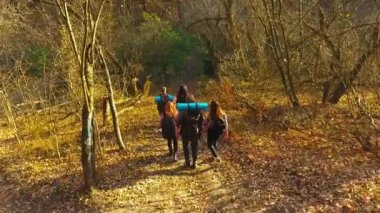 Genç turistler sonbahar ormanlarında sırt çantalarıyla yürüyüş yapıyorlar.