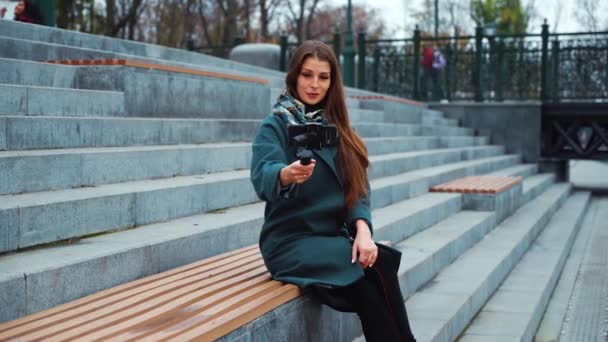 Pěkný vlogger streaming z městského parku pomocí smartphone a steadicam — Stock video