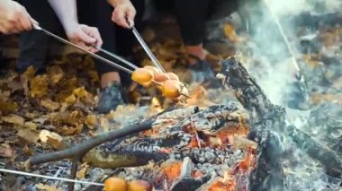 Neşeli turistler sonbahar ormanlarında kamp ateşinde piknik yapıyorlar.