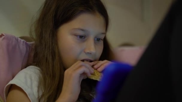 Niña usando tabletas y comiendo galletas — Vídeos de Stock