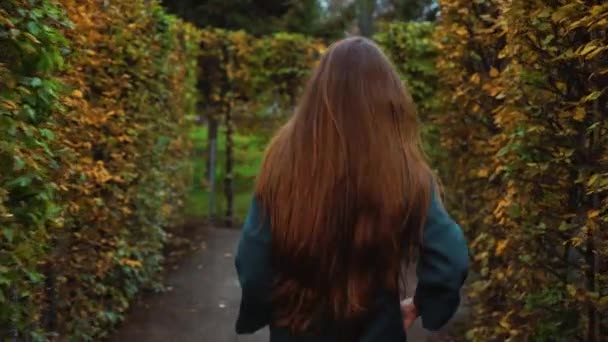 Vacker flicka promenader i trädgård labyrint på höstdagen — Stockvideo