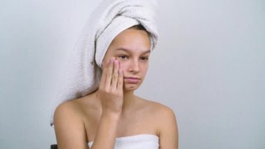 Banyo havlusu içindeki güzel genç kız sorunlu teninden memnun değil.