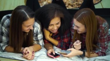 Mutlu kampçılar çadırda uzanıyor ve akıllı telefon kullanıyorlar.