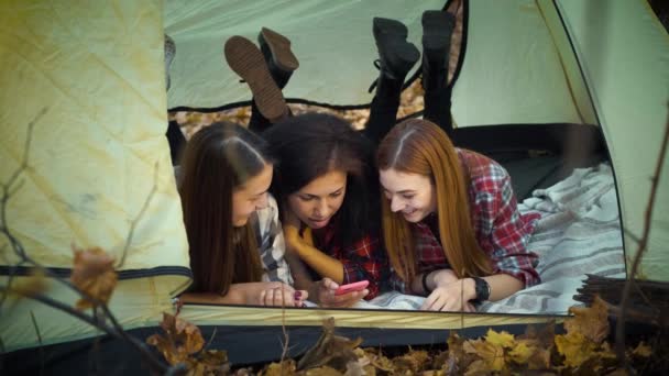 Happy tourists using smartphone lying in tent — ストック動画