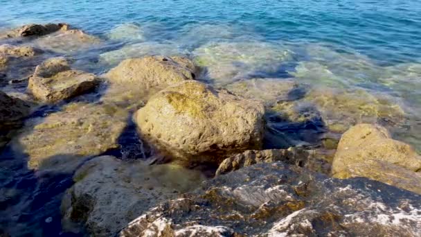 Морская вода брызгает на скалы, лежащие на берегу — стоковое видео