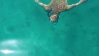 Kırmızı bikinili sporcu turistler su altında şnorkelle yüzüyor.