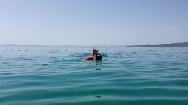 Счастливая пара туристов купается в синем море — стоковое видео