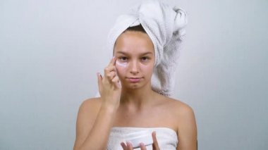 Sivilceli, banyo havlularına sarılı, yüz kremi sürmüş bir ergen.