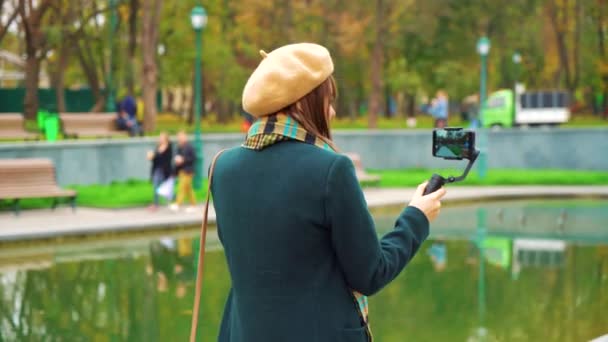 Δημοφιλή κορίτσι vlogger ζωντανά streaming από το πάρκο χρησιμοποιώντας το smartphone για steadicam — Αρχείο Βίντεο
