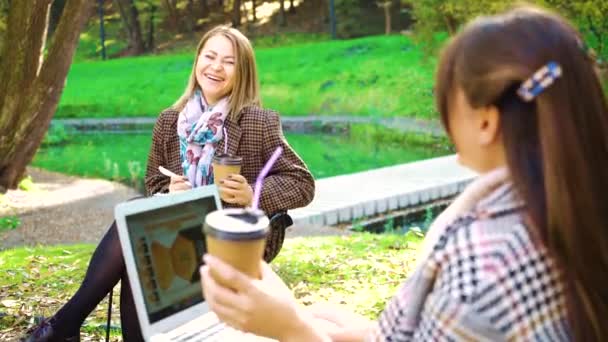 Веселые студенты с ноутбуком и кофе в осеннем парке — стоковое видео
