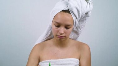 Banyo havlularına sarılı ergen kız mikiler suyuyla yüzünü temizliyor.