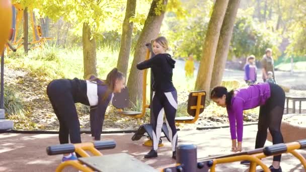 Fit girls stretching on sports ground on warm autumn day — ストック動画